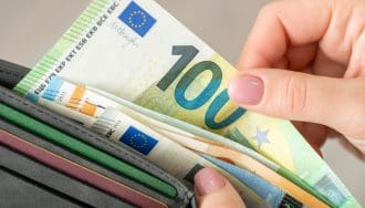 Ein Foto von einer Brieftasche mit mehreren Euro-Scheinen. Eine Hand zieht einen Hundert-Euro-Schein heraus.