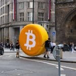 Ein großes Bitcoin-Logo in einer geschäftigen Stadt