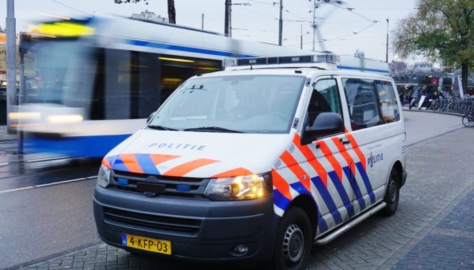 Ein Polizeiauto und/oder -van in Amsterdam, Niederlande, mit einer fahrenden Straßenbahn im Hintergrund