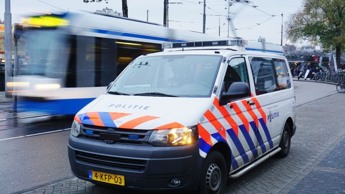 Ein Polizeiauto und/oder -van in Amsterdam, Niederlande, mit einer fahrenden Straßenbahn im Hintergrund