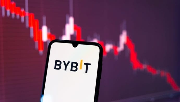 Das Logo der Krypto-Börse Bybit auf einem Mobiltelefon, mit einem roten Kursverlauf im Hintergrund, repräsentativ für den Kurs des gestohlenen Ethereum (ETH).