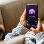 Frau auf der Couch mit einem Telefon und der Kraken-App