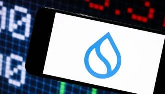 Ein Bild des Logos von sui (SUI) auf einem Mobiltelefon, mit Kryptomarktdaten oder einer Aktie im Hintergrund