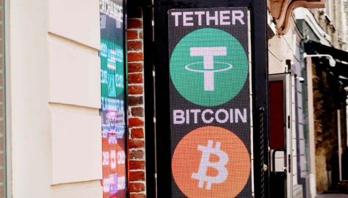 Ein Schild und eine Anzeige in einer belebten Straße, die zwei wichtige Kryptowährungen zeigen: Tether (USDT) und Bitcoin (BTC).