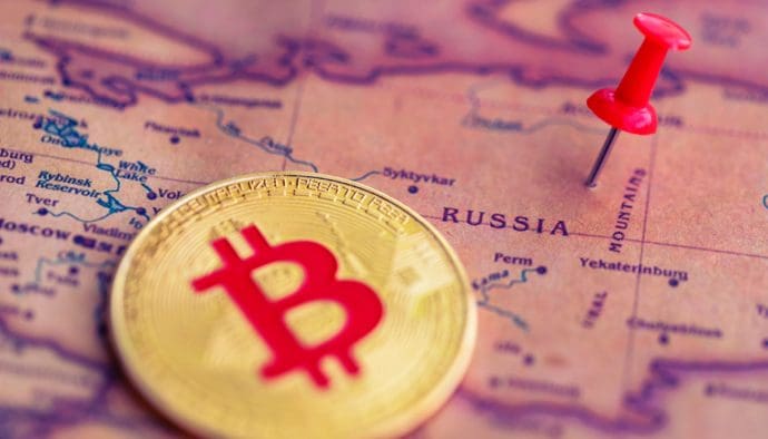 Eine Abbildung einer Bitcoin (BTC)-Münze neben einer Stecknadel auf dem Land Russland