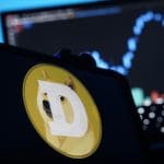 Een afbeelding van de cryptomunt dogecoin (DOGE) met daarbij het logo met de kenmerkende shiba inu mond, en op de achtergrond een grafiek van de koers Ein Bild der Kryptowährung Dogecoin (DOGE) mit dem Logo mit dem typischen Shiba-Inu-Mund und im Hintergrund ein Kursdiagramm.