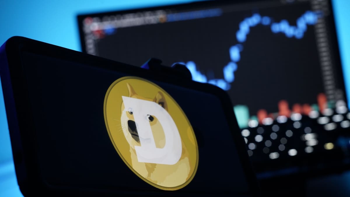 Een afbeelding van de cryptomunt dogecoin (DOGE) met daarbij het logo met de kenmerkende shiba inu mond, en op de achtergrond een grafiek van de koers Ein Bild der Kryptowährung Dogecoin (DOGE) mit dem Logo mit dem typischen Shiba-Inu-Mund und im Hintergrund ein Kursdiagramm.