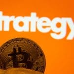 Een afbeelding van een aantal bitcoin munten met op de achtergrond het logo van Strategy, het bedrijf met de meeste bitcoin Börsen verbieten es Unternehmen, große Bitcoin-Reserven zu halten