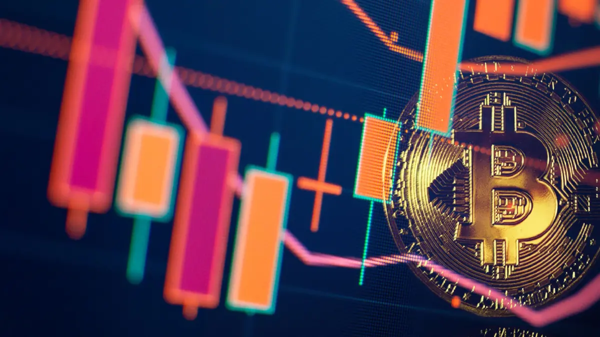 Ein Bild von einer Bitcoin (BTC)-Münze neben einem Candlestick-Chart, der einen leichten Kursrückgang zeigt, mit den dazugehörigen technischen Indikatoren.